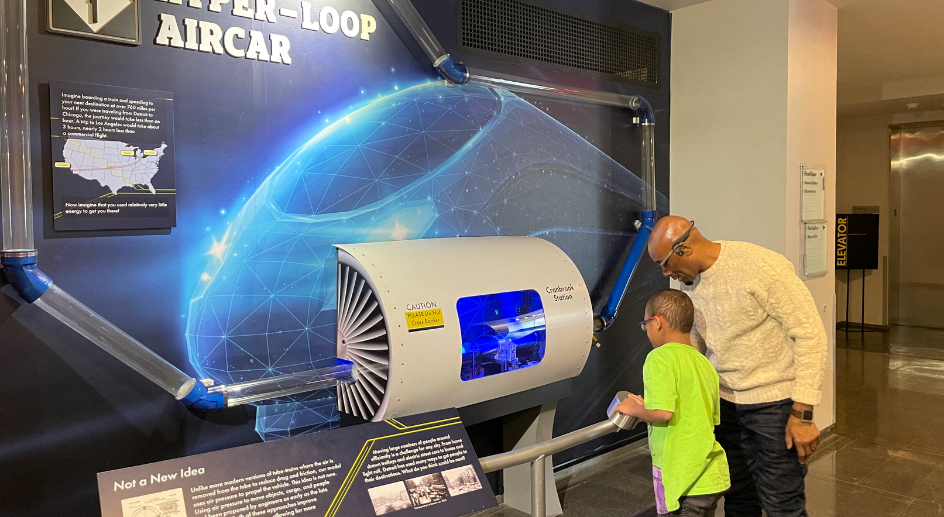 Staff showing a student how an exhibit works at Cranbrook Science Institute